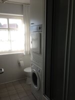 Badezimmer mit Dusche, Waschmaschine und Wäschetrockner